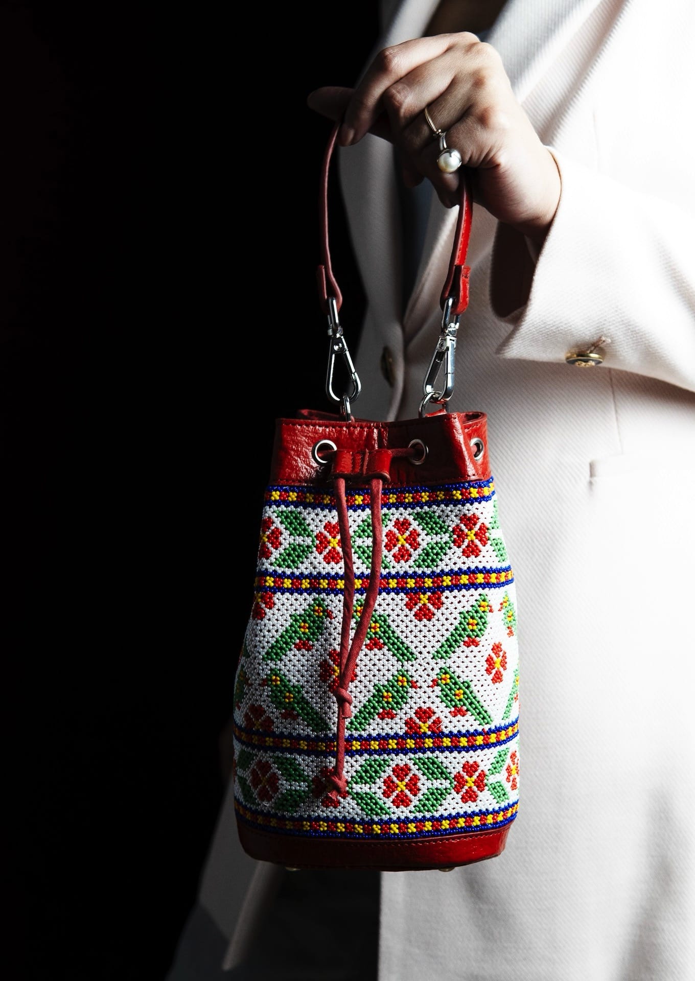 Eco-friendly hand-beaded drawstring potli held by its strap, premium Gujarati artisanal bag.