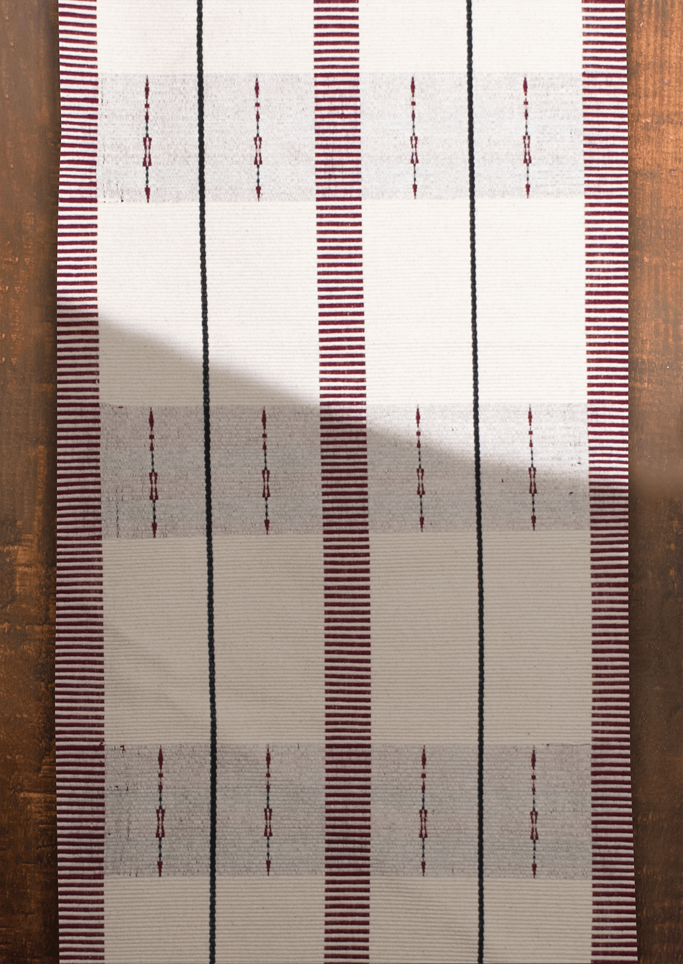 Handwoven cream cotton Angami table runner with maroon stripes, authentic Naga handicraft.