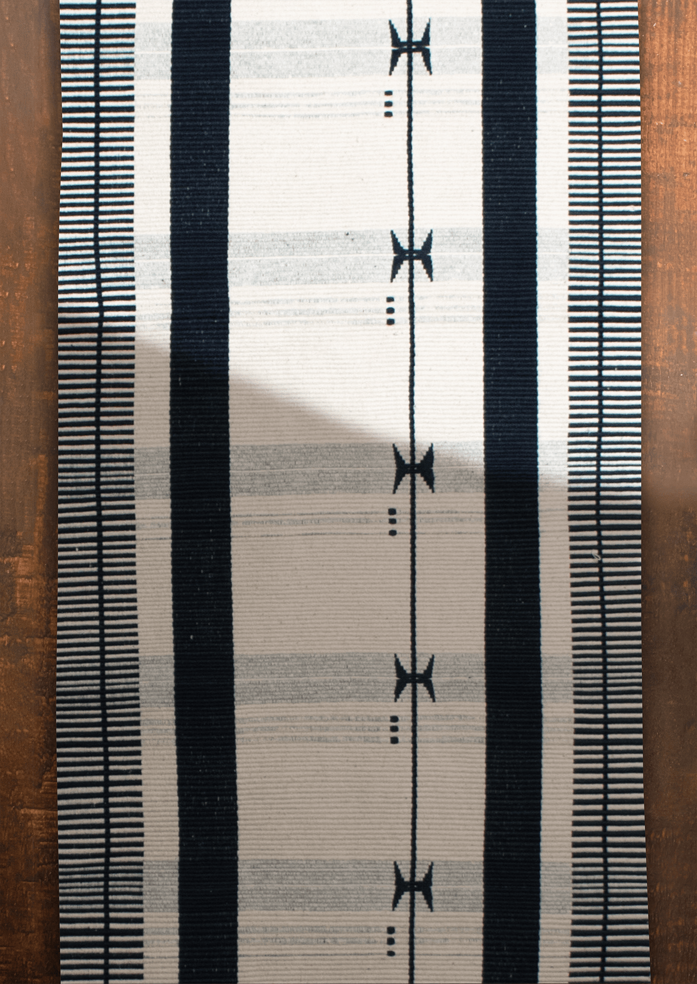 Handwoven black and white Kutsapo table runner with maroon details, traditional Naga loin loom art.