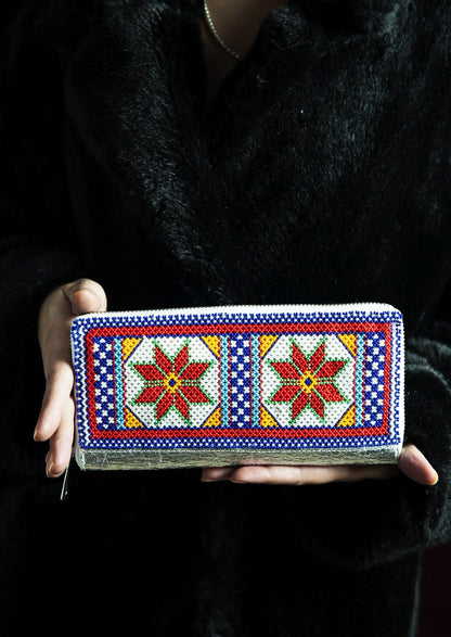 Intricate red and blue geometric dal-moti beadwork on a silver wallet displayed with hands, authentic artisanal craft.