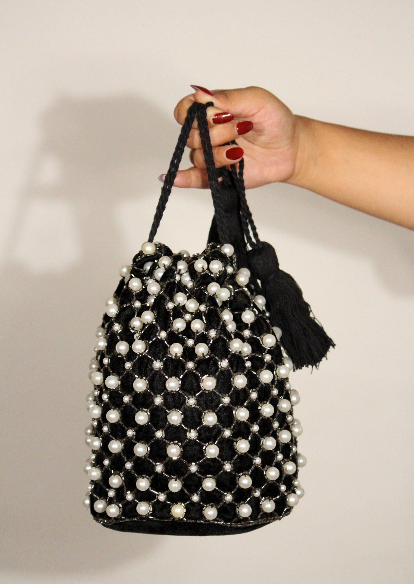 Elegant pearl-beaded drawstring potli bag held by hand, sustainable Indian luxury accessory.