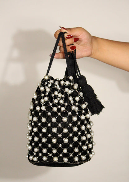 Elegant pearl-beaded drawstring potli bag held by hand, sustainable Indian luxury accessory.