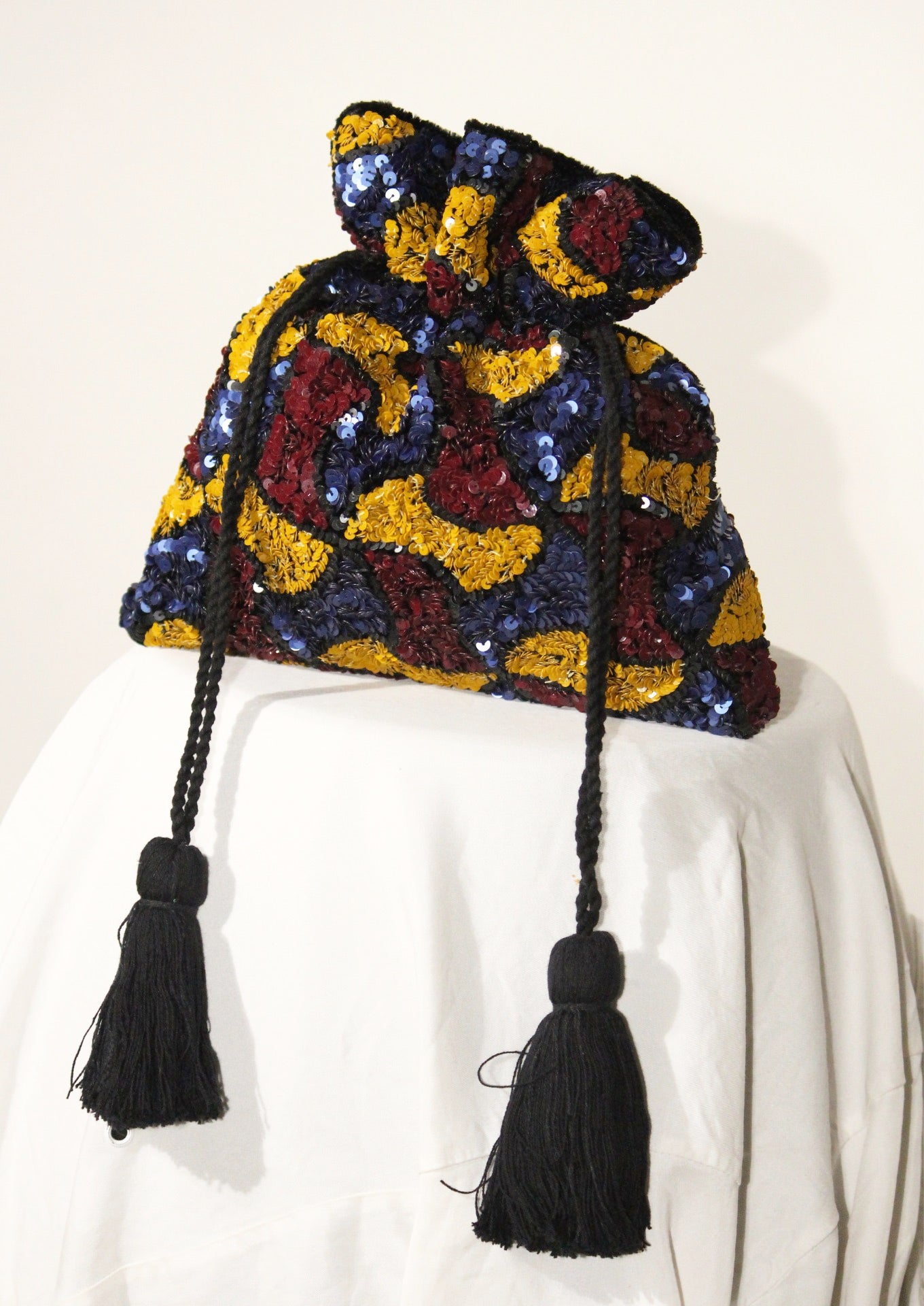 Colorful embroidered Segmenta potli bag with black tassels, sustainable Indian handicraft.