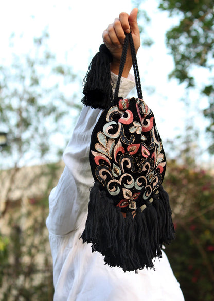 Hand-embroidered velvet drawstring potli held by hand, authentic Indian artisanal handbag.