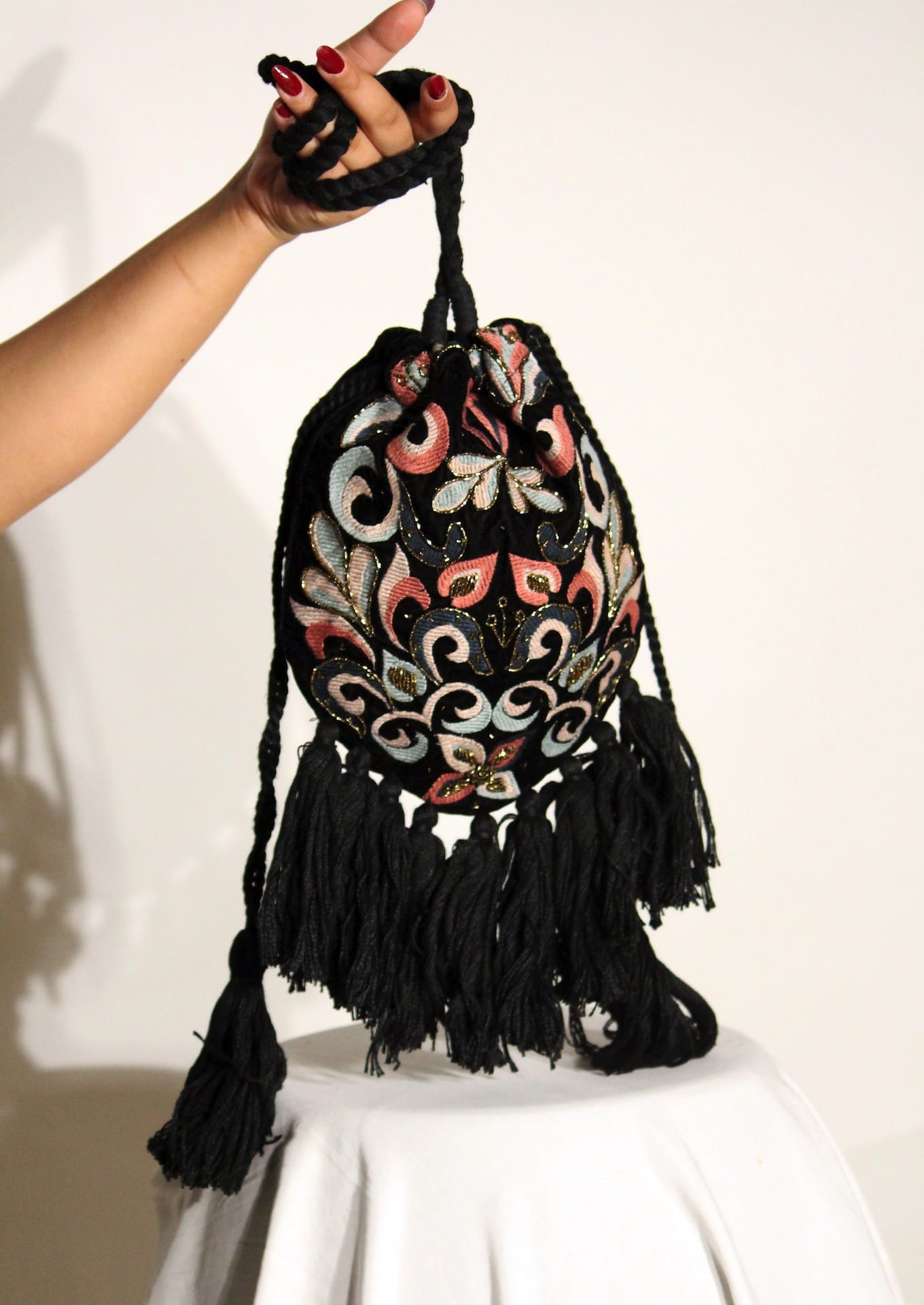 Hand-embroidered velvet drawstring potli held by hand, authentic Indian artisanal handbag.