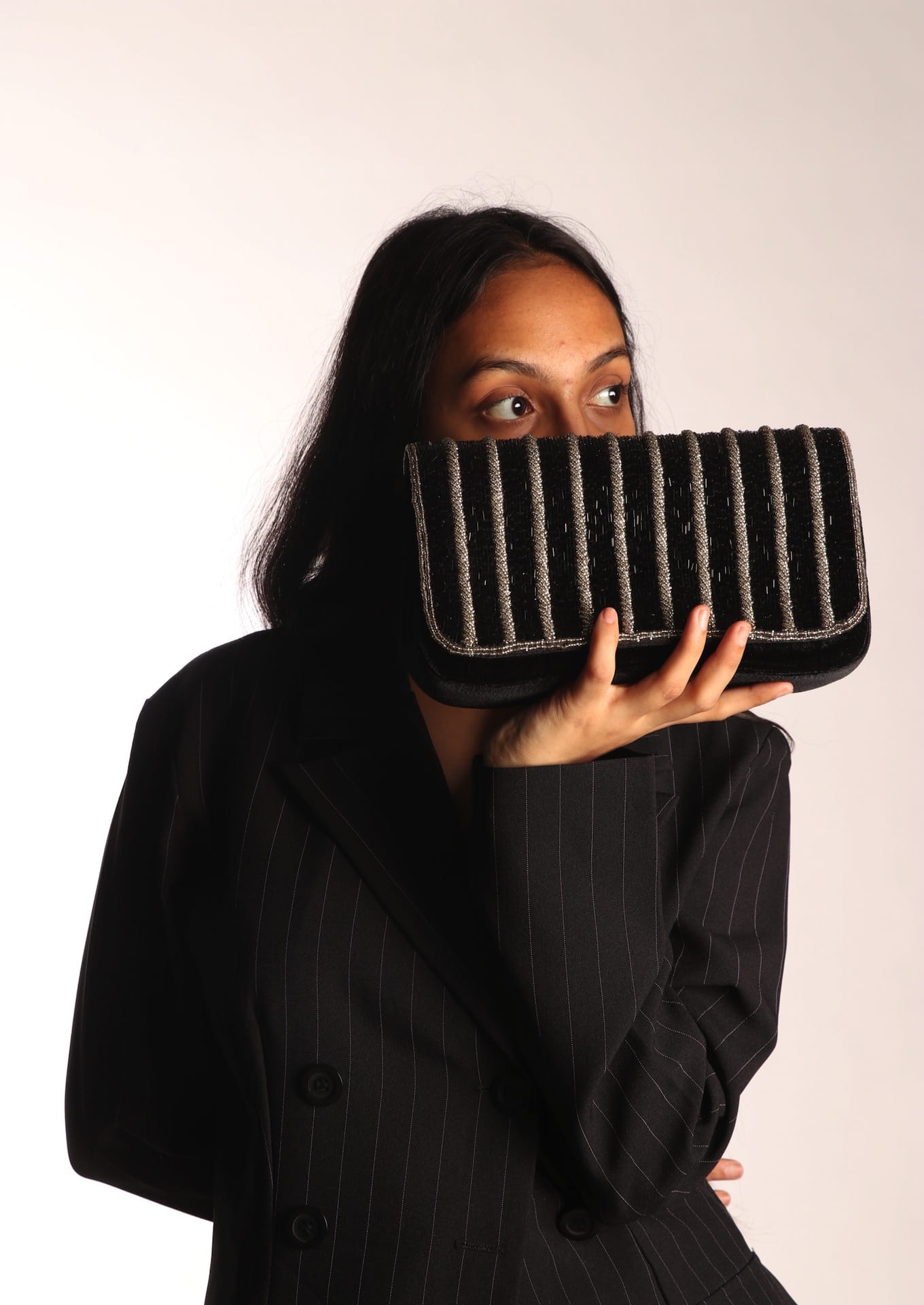 Rhythmic undulating silver beads on a rich black fabric clutch, Muradabad artisan craft.
